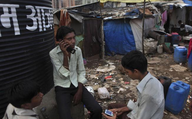 Young men on their mobile phones in a slum in Mumbai, India; a country where according to the United Nations, more people have mobile phones than access to a toilet. Photo: AP 