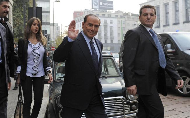 Silvio Berlusconi waves as he arrives yesterday at the court hearing in Milan, at which he denied hosting kinky parties. Photo: AP
