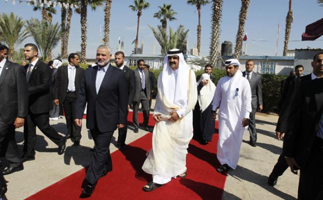 Qatari Emir Sheikh Hamad bin Khalifa al-Thani (centre-right) walks alongside Gaza's Hamas prime minister Ismail Haniyeh (centre-left) during a welcome ceremony at the Rafah border crossing with Egypt on Tuesday. Photo: AFP
