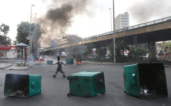 Lebanese cross between burning tyres and garbage containers laid by protesters after overnight clashes between Sunni and Shiite gunmen, in Beirut, Lebanon on Monday. Photo: AFP