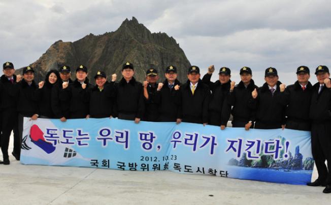 Members of South Korea's parliamentary National Defence Committee hold a banner reading 'Dokdo is Korean territory, we defend!' during a visit to the Dokdo islands (known as Takeshima in Japan) on Tuesday. Photo: AFP