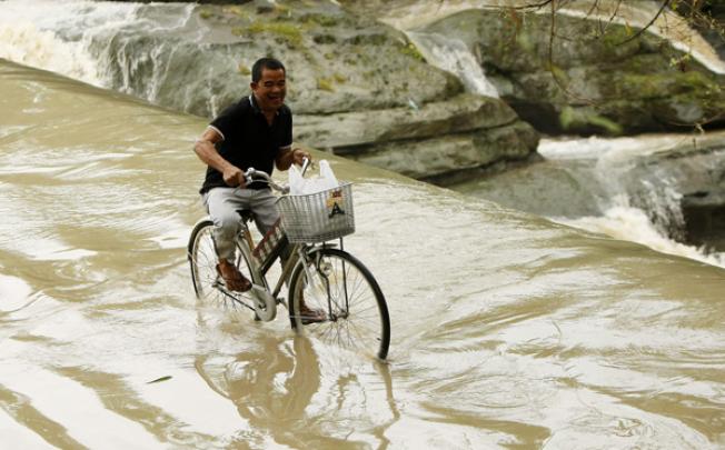 A man crosses a swollen river in Las Pinas city, south of Manila, on Friday. Photo: EPA