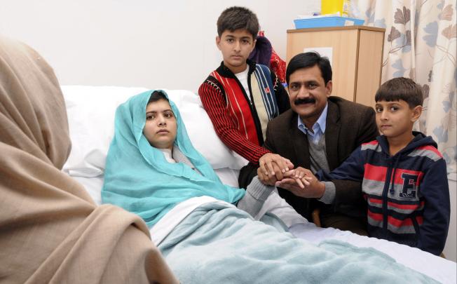 Malala Yousufzai in her hospital bed, with her father Ziauddin (second right) accompanied by her two younger brothers Atal (right) and Khushal (centre). Photo: AP