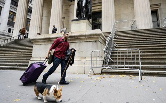 A New York resident, who is packed up and leaving on evacuation orders, passes the New York Stock Exchange in lower Manhattan. Photo: AFP