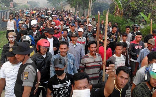 Villagers carry wooden sticks during clashes in Lampung. Photo: EPA