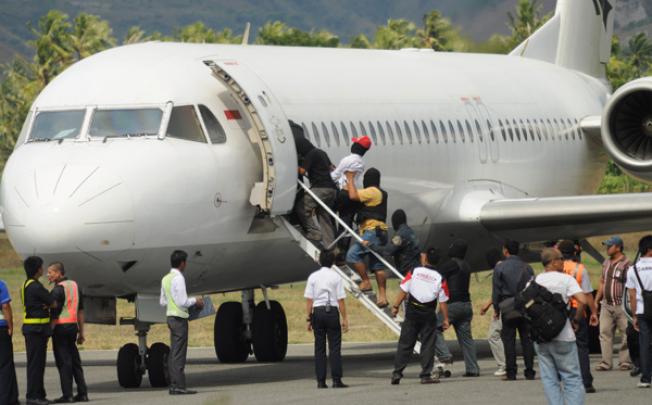 Terror suspects are escorted into a plane at Mutiara airport by anti-terror police in Palu, Sulawesi, on Wednesday. Photo: AFP
