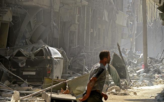 A resident of Aleppo walks past buildings destroyed during shelling by Syrian regime forces in early October. Photo: AP
