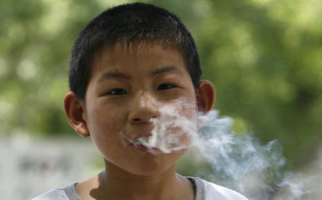 A 7-year-old Chinese boy exhales from his cigarette. Children using menthol cigarettes are more likely to become habitual smokers, a study has found. Photo: EPA