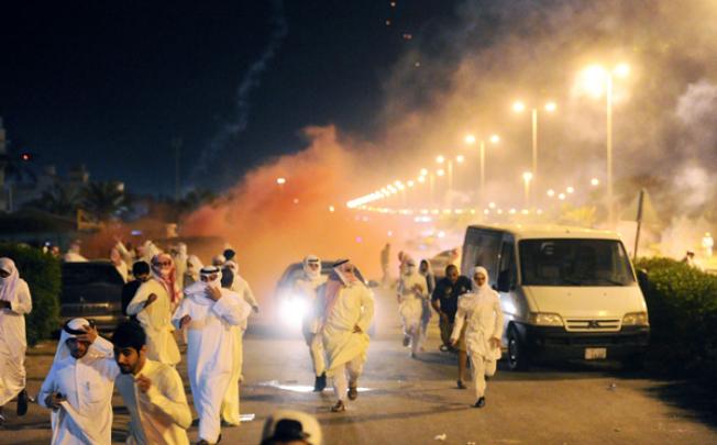 Protesters run for cover as Kuwait riot police used stun grenades and tear gas to disperse thousands of angry demonstrators on Wednesday. Photo: AFP