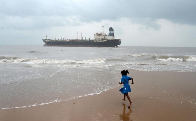An Indian girl runs on the beach near the Pratibha Cauvery, which ran aground during Cyclone Nilam, on Thursday. Photo: Xinhua