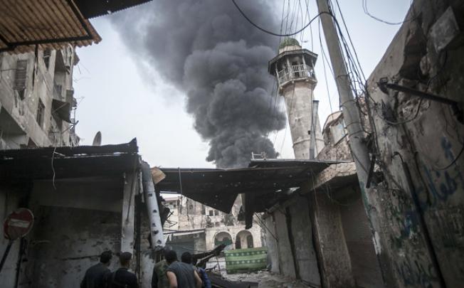 Rebel fighters watch as smoke rises after Syrian government forces fired an artillery round at a rebel position during heavy clashes in Aleppo on Sunday. Photo: AP