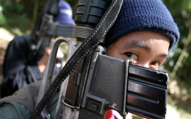 A female New People's Army (NPA) guerilla covers her face with an M16 armalite rifle. Photo: EPA