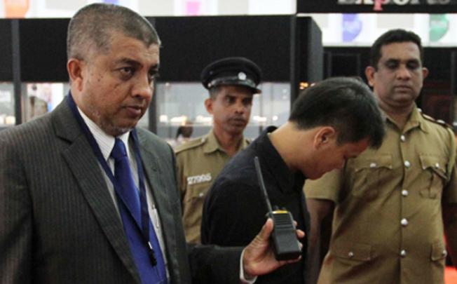 A Sri Lankan security official and a uniformed policeman escort a Chinese national accused of stealing a US$13,800 diamond by swallowing it. Photo: AFP