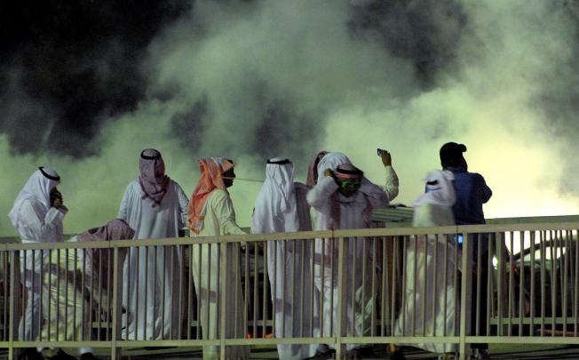 Kuwaiti protesters put on goggles and turn away from a cloud of smoke fired by police during protestw against new voting rules for parliamentary elections on December 1. Photo: EPA