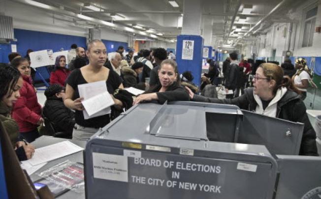 BA poll worker (far right) give instructions to voters arriving from a relocated polling site that closed after flooding from superstorm Sandy, on Tuesday. Photo: AP
