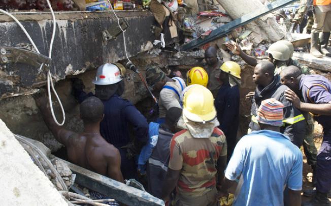 Rescue workers drill into the roof of a collapsed shopping mall that killed at least seven people and trapped dozens of others on Wednesday in Accra. Photo: AFP 