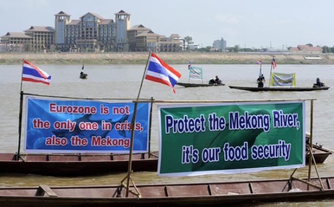 Thai activists and villagers who are affected by the controversial Xayaburi dam protest with with banners on the Mekong riveron Monday. Photo: EPA