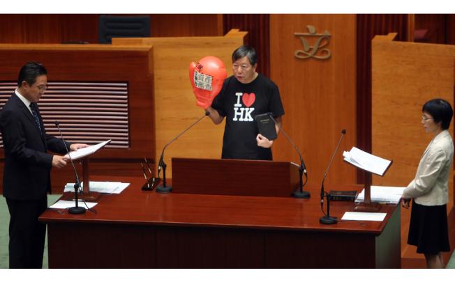 Lawmaker Lee Cheuk-yan (centre) takes an oath at Legislative Council in Tamar wearing a boxing glove to protest against old-age allowance means test.