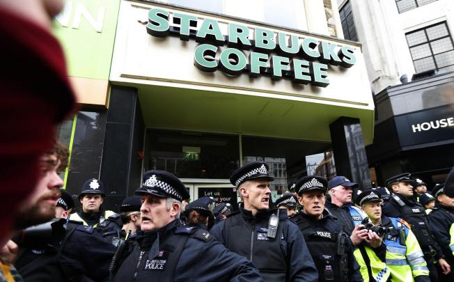 Police protect a Starbucks branch during an anti-cuts march last month after the company's low tax bill was reported. Photo: Reuters