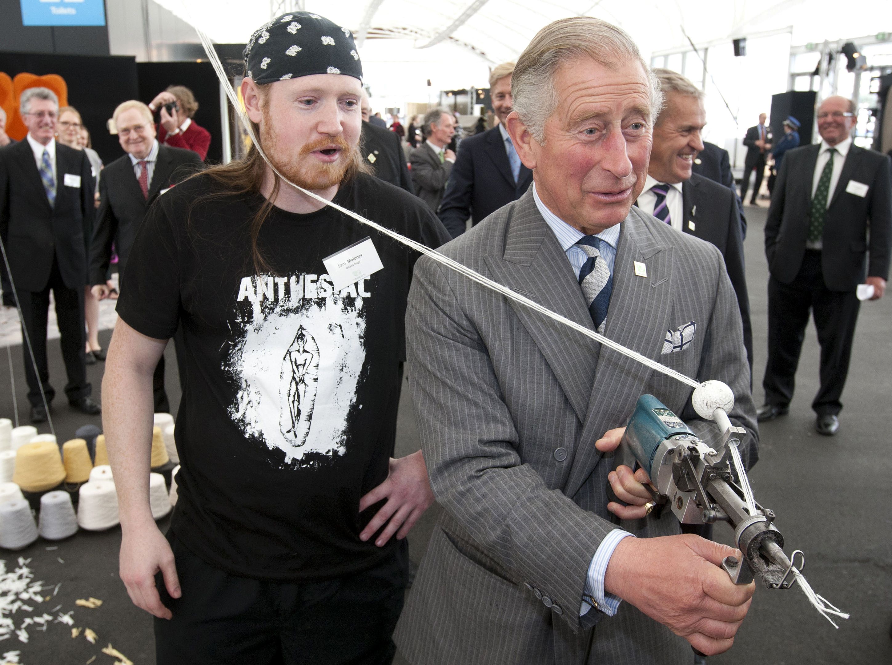 Prince Charles jests with the media as he tries his hand at making a wool rug with the help of Sam Maloney during a wool promotion in Auckland on Monday. Photo: AFP
