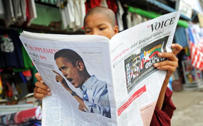 A Buddhist monk reads a local newspaper carrying a picture of US President Barack Obama in Yangon on Saturday. Photo: AFP