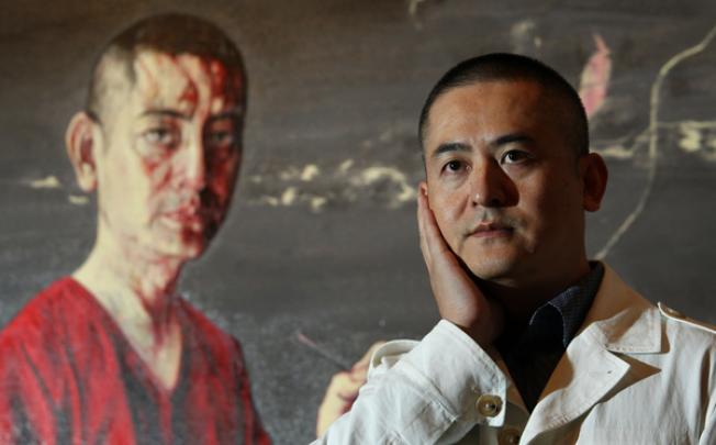 Zeng Fanzhi poses next to one of his paintings. Photo: May Tse