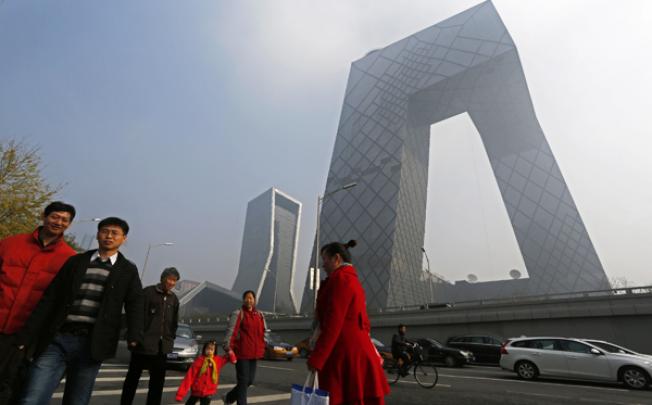 Residents walk past the iconic CCTV building in Beijing. Photo: AP