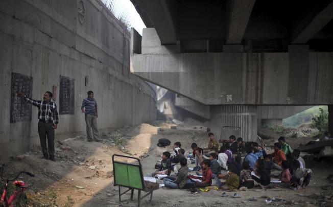 Classes in session at a free school for impoverished slum children run under a metro bridge in New Delhi, India. Photo: AFP