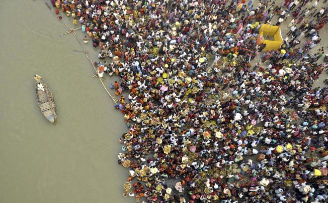 Hindu devotees take part in worship on the banks of the River Ganges river during Chhath festival. At least 18 people were killed in a stampede after a bridge collapsed. Photo: AP