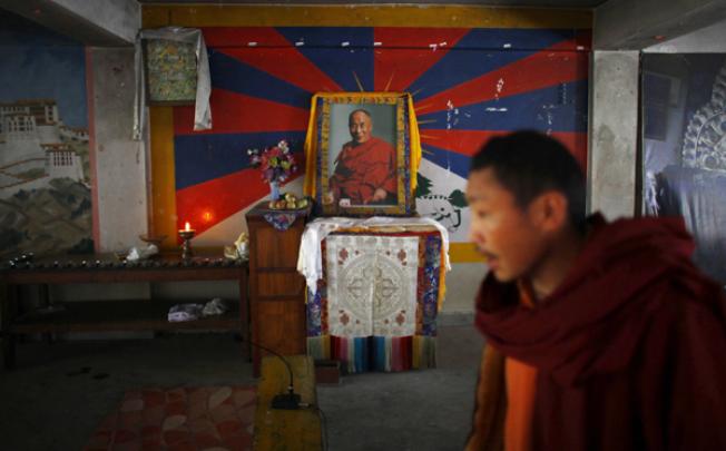 An exiled Tibetan monk walks past a portrait of spiritual leader the Dalai Lama during a prayer ceremony to display solidarity towards Tibetans who have self-immolated, protesting China's rule, in Katmandu on Saturday. Photo: AP
