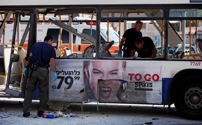 Police examine a bus that was hit by a blast in Tel Aviv yesterday, injuring 27 people in an apparent terrorist attack. Hours later it was announced in Cairo that Israel and Hamas had agreed to a ceasefire in Gaza. Photo: AP