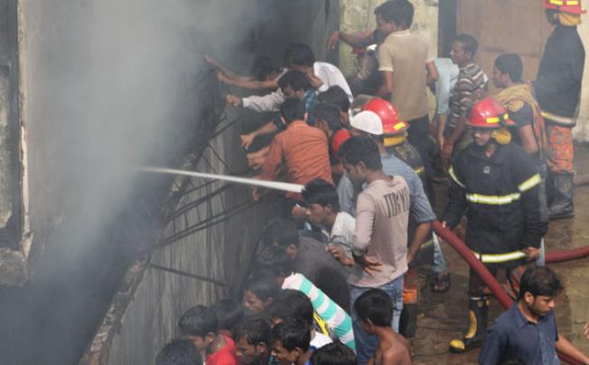 Firefighters and local people try to extinguish a fire at a garment factory in Dakkhin Khan in Dhaka on Monday. Photo: Xinhua