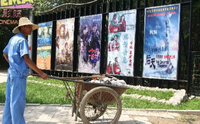 A worker pauses by cinema posters advertising Chinese and English language films in Beijing. Photo: Bloomberg