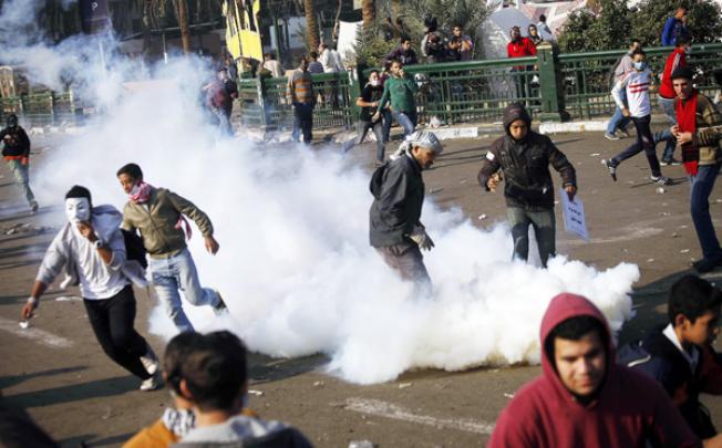 Demonstrators run away from tear gas during clashes with riot police on Omar Makram street, off Tarir Square, on Wednesday. Photo: AFP