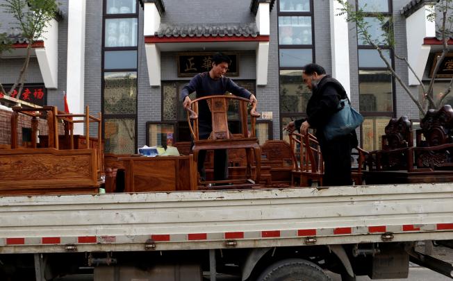 Workers load Chinese-style furniture made of African rosewood outside a Beijing furniture shop. China is making tentative efforts to import rosewood and other species from legal sources, having established several bodies to regulate the trade.
