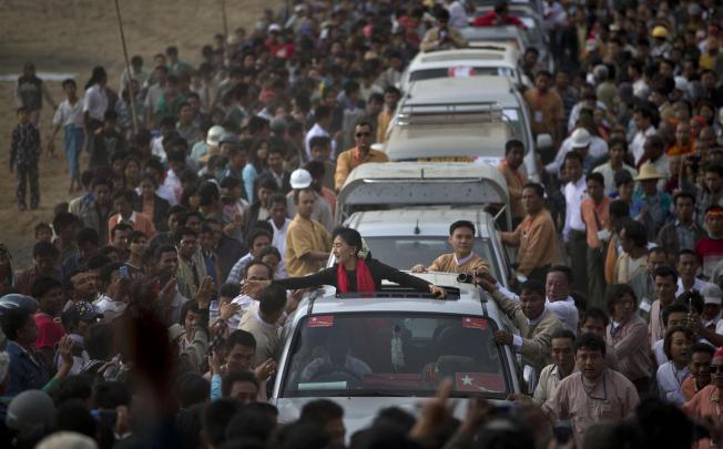 Opposition leader Aung San Suu Kyi reaches out to supporters as she leaves after a public meeting close to Letpadaung mine. She has taken a soft line on the conflict, suggesting Myanmar honour the mining contract. Photo: AP