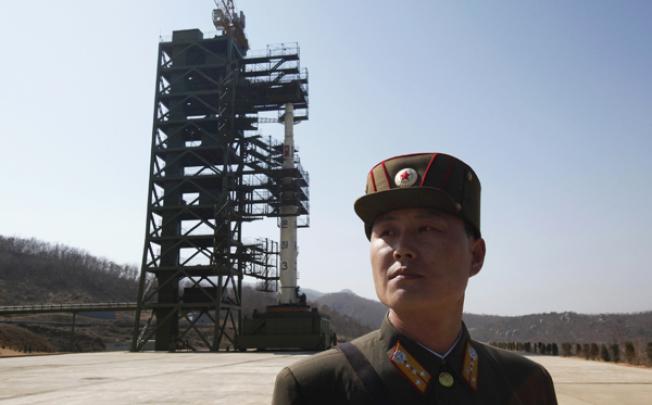 A soldier stands guard in front of a rocket sitting on a launch pad at the West Sea Satellite Launch Site, northwest of Pyongyang, in April. Photo: Reuters