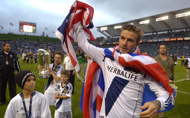 LA Galaxy's David Beckham, right, waves to fans as his sons from left, Romeo, Brooklyn and Cruz follow after winning the MLS Cup championship match 3-1 against the Houston Dynamo on Saturday. Photo: AP