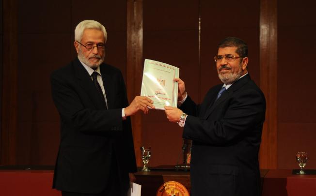 Egyptian President Mohamed Mursi (right) receives the final draft of Egypt's constitution from Hossam El-Gheriany, head of the Constituent Assembly on Saturday. Photo: Xinhua