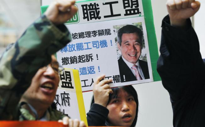 Members of a labour union hold placards with pictures of Singapore's Prime Minister Lee Hsien Loong reading 'Release the striking bus driver, restrict a charge' near the Singapore Consulate General in Hong Kong on Wednesday. Photo: AP