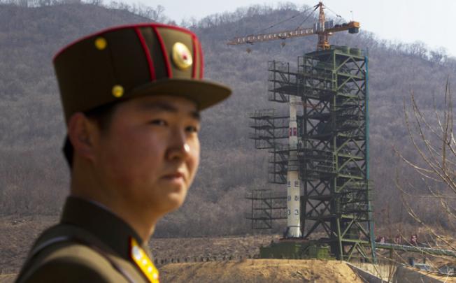 A North Korean soldier stands in front of an Unha-3 rocket, slated for lift-off as early as next week, at a launching site in Tongchang-ri. Photo: AP