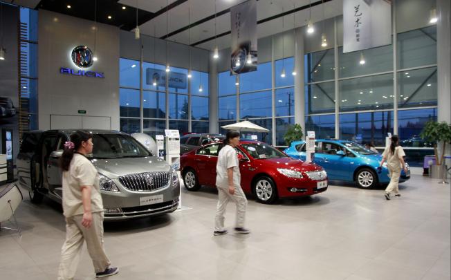 Staff walk past vehicles on display at the GM Buick Yongda dealership in Shanghai.  General Motors, the biggest foreign automaker in China, reported a 9.7 per cent rise in November sales to 260,018 units, led by its Chevrolet and Buick brands, outpacing an 8.75 per cent rise in the broader market.  Photo: Bloomberg