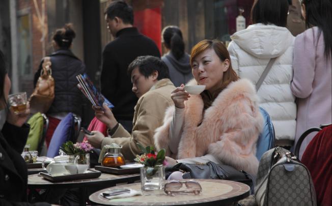 A woman sips tea in Tianzifang, Shanghai. Up to 200 million city dwellers have no residency status. Photo: Corbis
