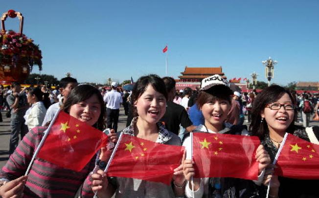 Visitors with the national flags in hands pose for photos on the Tian'anmen Square. Photo:Xinhua