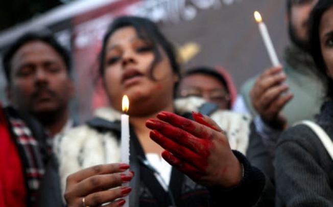 An Indian protester, with hands colored in fake blood, holds a candle during a protest campaign. Photo: EPA