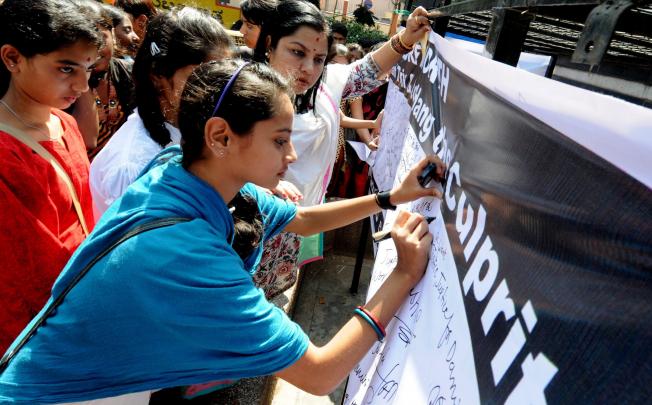 Indian protesters and members of the Akhil Bharatiya Vidyarthi Parishad (ABVP) write a message to Indian Prime Minster during a signature campaign towards violence against women. Photo: EPA