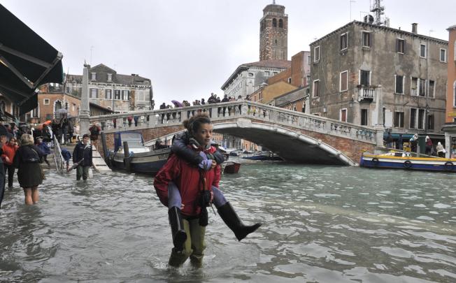 People walk in high water near the Ponte delle Guglie in Venice, Italy. Joseph Stiglitz says global warming is one of the long-term problems our world is facing. Photo: AP 