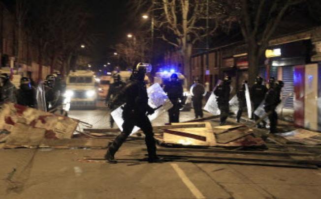 Police dressed in riot gear clear Tempelmore of debris placed there by loyalist youths in Belfast. Photo: Reuters