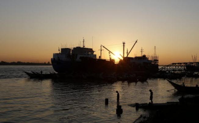 The sun sets behind a ship moored at Yangon port, Myanmar. Photo: EPA
