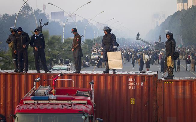Pakistani police officers stand guard on a barricade made shipping containers in Islamabad on Tuesday. Photo: AP